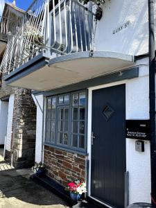 Casa con puerta negra y balcón en Beautiful Quayside Cottage Looe, en Looe
