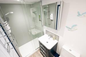Un baño blanco con ducha y lavabo. en Beautiful Quayside Cottage Looe, en Looe