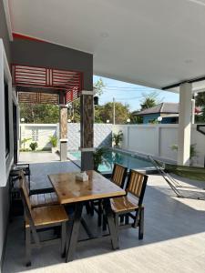 a wooden table and chairs on a patio with a pool at PoolvillaLana 3 rooms in Bang Sare