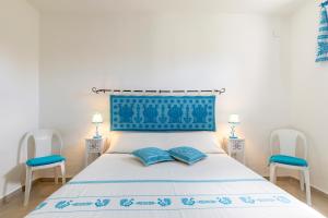 1 dormitorio con 1 cama con 2 sillas azules en Casa Paola, en Tortolì