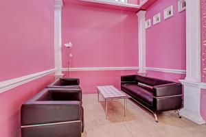 a pink room with a couch and a table at Hotel O Amole Homestay Syariah in Cilacap