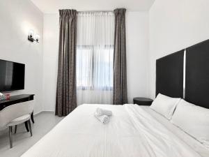 a bedroom with a white bed with a desk and a window at Al Manara Classic Deluxe Studio in Dubai
