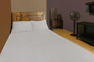 a bedroom with a large white bed and a fan at OYO 92308 Kos Duduk in Lajor