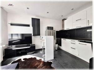 a kitchen with white and black cabinets and a chair at Apartman Naty in Banská Bystrica