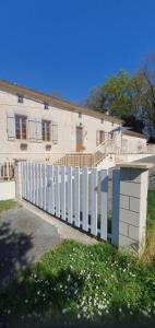 a white fence in front of a white building at maison 2 chambres au calme in Saint-Bonnet-sur-Gironde