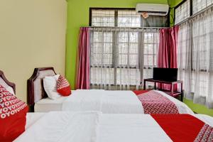 a bedroom with two beds and a window at Hotel O Rindu Sempadan Cottage Near Taman Wisata Rindu Sempadan in Pekanbaru