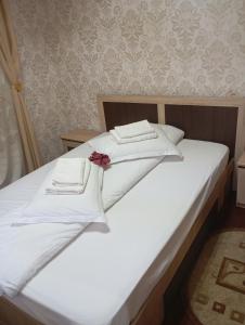 ein weißes Bett mit weißen Handtüchern und einem roten Bogen in der Unterkunft Casa Rania si Ayan Sătic Rucăr in Ciocanu