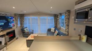 a living room with a couch and a tv at Lighthouse Lodge - Peaceful & Dog Friendly in Sutton on Sea