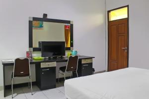 a bedroom with a desk with a computer and two chairs at Collection O near Radin Inten II Airport formerly Hotel Aero in Negarasaka