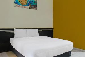 a bed with white sheets in a room at Collection O near Radin Inten II Airport formerly Hotel Aero in Negarasaka +20 photos