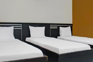 two beds in a room with white sheets and pillows at Collection O near Radin Inten II Airport formerly Hotel Aero in Negarasaka