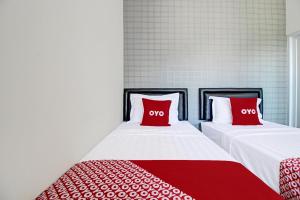 two beds with red pillows in a room at Collection O 92363 Kp Inn in Yogyakarta