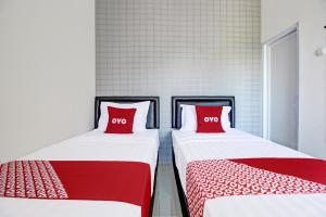 two beds with red pillows sitting next to each other at Collection O 92363 Kp Inn in Yogyakarta