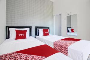two beds with red pillows in a room at Collection O 92363 Kp Inn in Yogyakarta