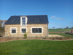 ein Steinhaus mit schwarzem Dach auf einem grünen Rasen in der Unterkunft Maison Beniguet 6 places proche Paimpol et Tréguier in Pleumeur-Gautier