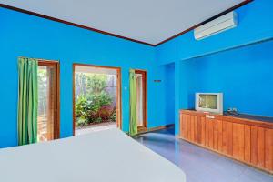 a blue room with a bed and a tv at Hotel O Mustika in Mendaya