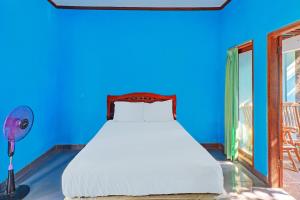 a bed in a room with a blue background at Hotel O Mustika in Mendaya