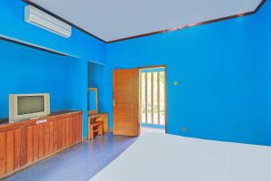 a blue room with a television and a door at Hotel O Mustika in Mendaya +30 photos