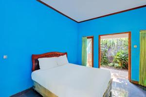 a blue bedroom with a bed and a window at Hotel O Mustika in Mendaya