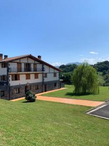 a building with a grassy field next to a road at casa rural larre aundi in Rentería