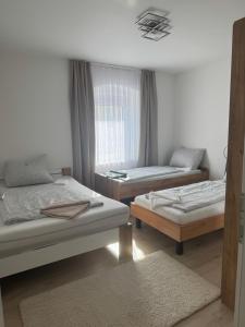 a room with three beds and a window at Wohnungen Beshi Niederthalheim in Vöcklabruck