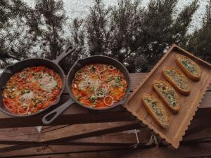 two pans of pizza and some bread on a table at Bonanza Terra in Rukliai