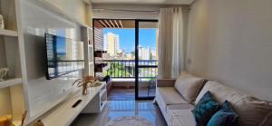ein Wohnzimmer mit Couch und großem Fenster in der Unterkunft CORVE0106 - Condomínio Villa di Capri in Salvador