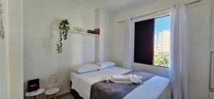 ein weißes Schlafzimmer mit einem Bett und einem Fenster in der Unterkunft CORVE0106 - Condomínio Villa di Capri in Salvador