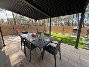 a black table and chairs on a patio at Maison neuve classement 3 étoiles avec accès privé piste cyclable, 6 personnes in Mimizan