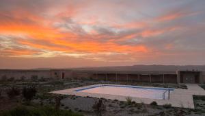 a swimming pool in the desert with a sunset at DAR AL QANASS IMANE in Midelt