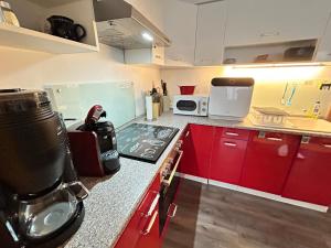 a kitchen with red cabinets and a counter with a coffee maker at Ferienwohnung Joli- inklusive Parkplatz, Bettwäsche, Handtücher und WLAN in Weißenfels