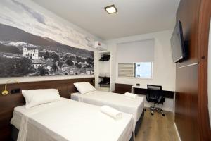 ein Hotelzimmer mit zwei Betten und einem Schreibtisch in der Unterkunft North Savassi in Belo Horizonte