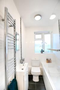 a white bathroom with a toilet and a sink at 2BR Near Tottenham Stadium - WiFi - Free Parking in Ponders End