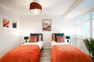 two orange and white beds in a room at 2BR Near Tottenham Stadium - WiFi - Free Parking in Ponders End