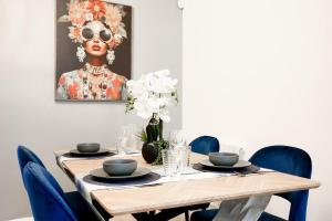 a dining room table with blue chairs and a painting at 2BR Near Tottenham Stadium - WiFi - Free Parking in Ponders End