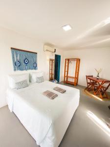 a bedroom with a white bed with two towels on it at Pousada La Grécia in Camocim