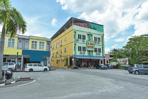 a tall yellow building with cars parked in a parking lot at Hotel O Pendang Lake Formerly D Jiwa in Pendang