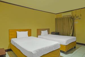 two beds in a room with yellow walls at Hotel O Azeela Kost Syariah in Banjarmasin