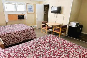 a hotel room with two beds and a table and a television at Love Hotels Timberline By OYO Lake Superior in Ironwood