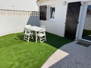 a white table and two chairs on a patch of grass at Anisades, Maison cosy avec jardin 5 min plage in Le Barcarès