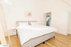 a bedroom with a large white bed and a mirror at 119 QM - Exklusiv auf 2 Etagen - Werse Loft by youpartments in Münster