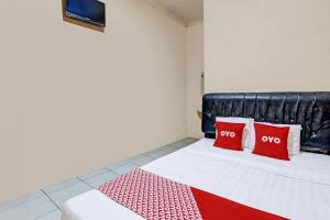 a bed with two red pillows on top of it at OYO 92459 Cahyo Kost 2 in Semarang