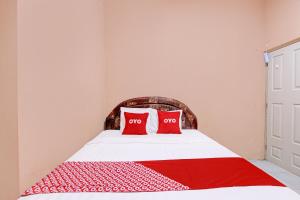 a bedroom with a bed with two red pillows at OYO 92459 Cahyo Kost 2 in Semarang