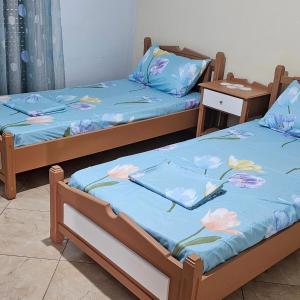 two beds with blue sheets with flowers on them at Villa Topuzi Second Floor in Pogradec