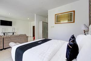 ein Schlafzimmer mit einem großen weißen Bett und einem Fernseher in der Unterkunft Collection O Gunung Kidul Near Baron Beach Formerly Orchid Hotel in Duwet