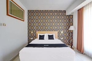 ein Schlafzimmer mit einem weißen Bett und einer Wand in der Unterkunft Collection O Gunung Kidul Near Baron Beach Formerly Orchid Hotel in Duwet