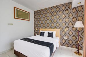 ein Schlafzimmer mit einem Bett und einer Wand in der Unterkunft Collection O Gunung Kidul Near Baron Beach Formerly Orchid Hotel in Duwet