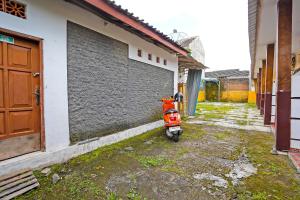 a red scooter parked next to a building at SPOT ON 92475 Rc Homestay Syariah in Banyuwangi +18 photos