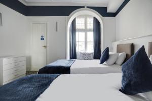 two beds in a bedroom with a window at Lord Kitcheners Guest House in Lowestoft