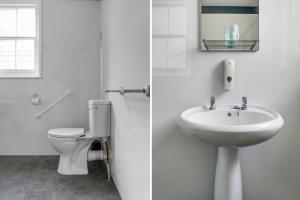 a white bathroom with a toilet and a sink at Lord Kitcheners Guest House in Lowestoft